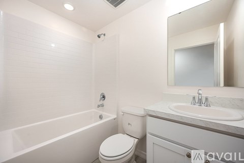A white bathroom with a toilet, sink, and bathtub.