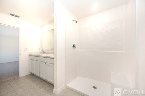 A white bathroom with a sink and a shower.