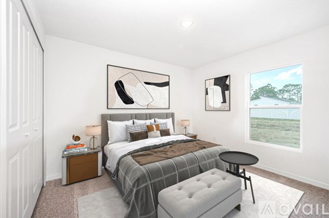 A bedroom with a large bed, a nightstand, a side table, and a window with a view of a beach.