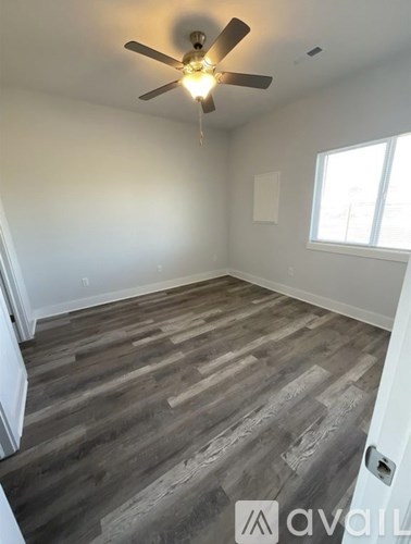 A room with a ceiling fan and wooden flooring.