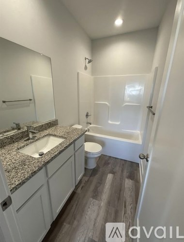 A bathroom with a sink, mirror, toilet and bathtub.