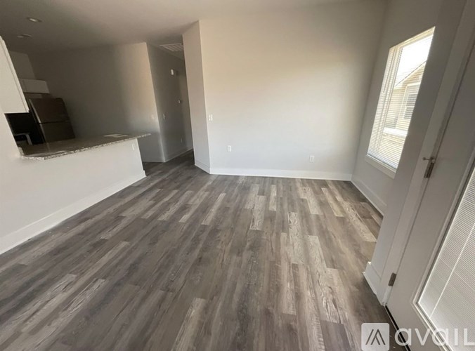 A room with wooden flooring and white walls.