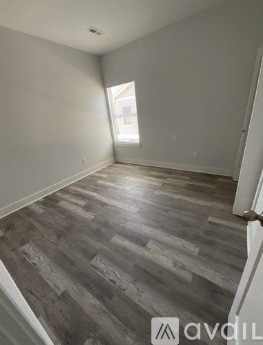 A room with wooden flooring and a window.