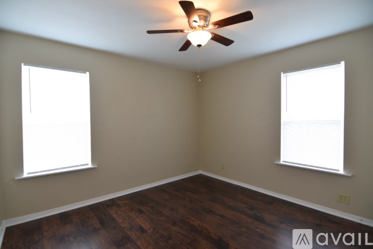 A room with a brown floor and a ceiling fan.