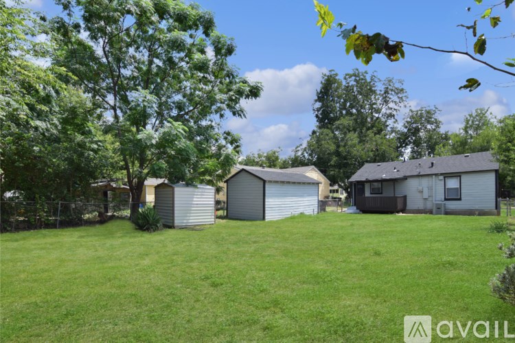 A grassy area with a few houses and trees.
