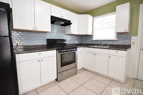 A kitchen with white cabinets and a black refrigerator.