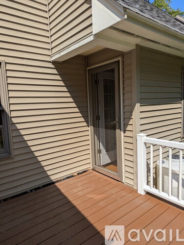 A deck with a white railing and a sliding glass door.