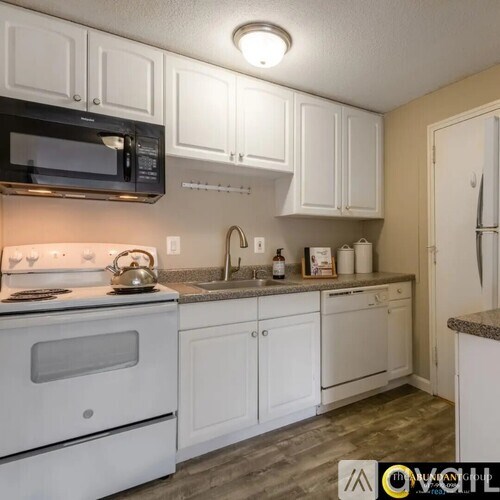 A kitchen with white cabinets and a black microwave.