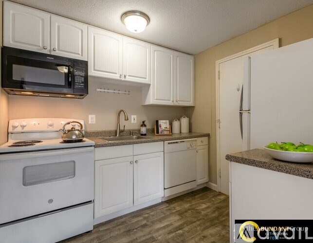 A kitchen with white cabinets and a black microwave.
