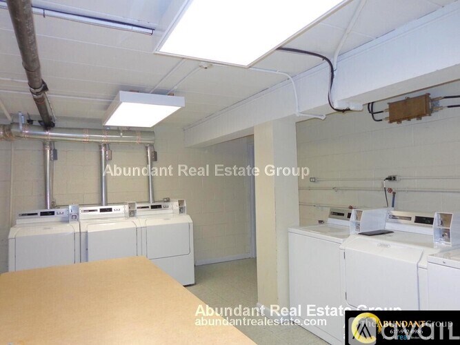 A laundry room with washers and dryers, and a sign that says Abundant Real Estate Group.