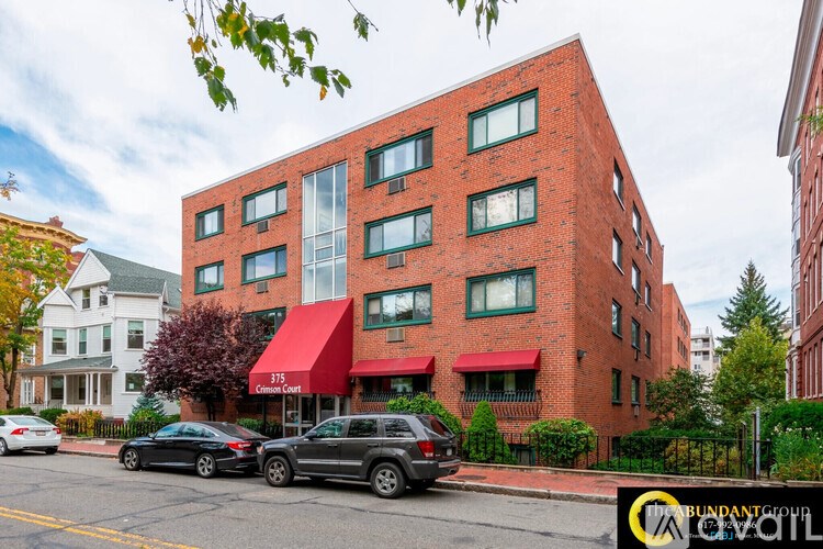 A red brick building with a green awning and a sign that says "115 Commercial Court".