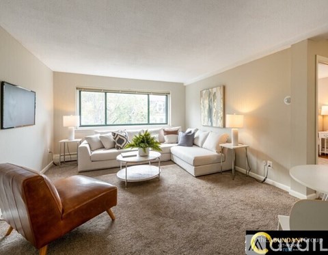 A living room with a brown leather chair and white couches.