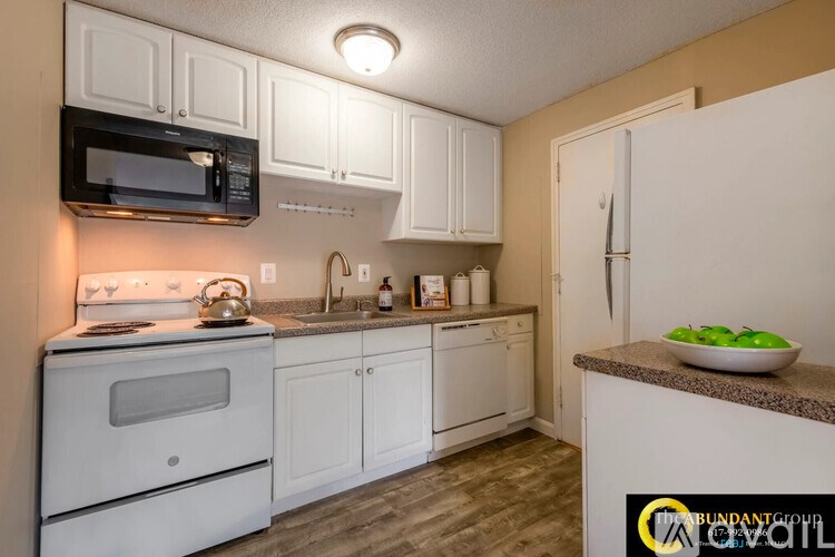 A kitchen with white cabinets and a white oven.