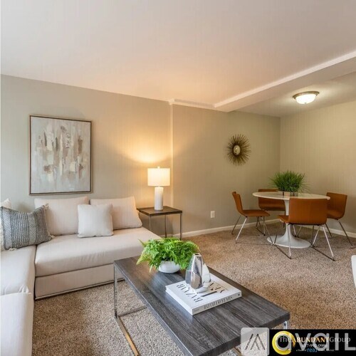 A living room with a white couch, a coffee table, and a dining table set up.
