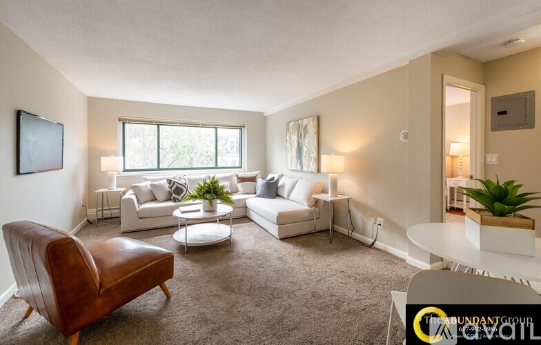 A living room with white furniture and a brown leather chair.