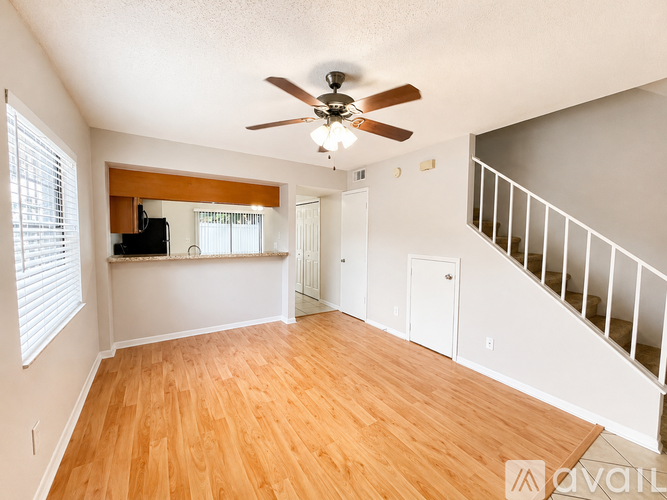 A spacious room with a staircase and a ceiling fan.