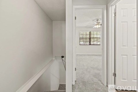 A hallway with a staircase leading to a bedroom.