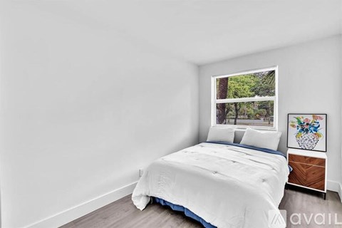 A bedroom with a large bed and a window showing trees outside.
