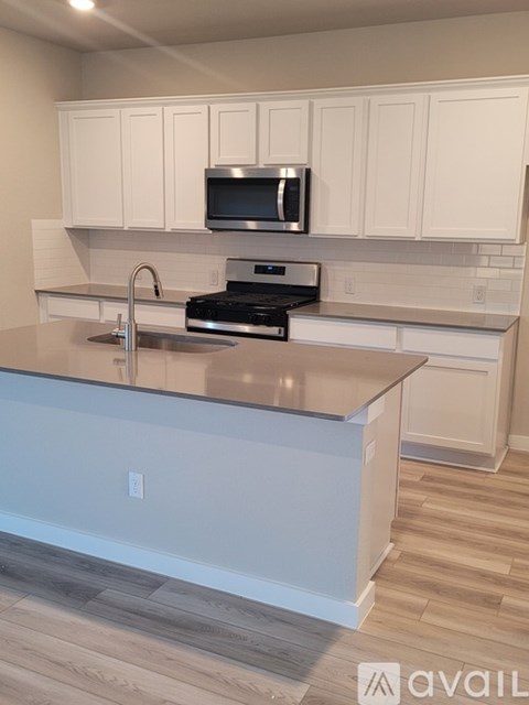 A kitchen with white cabinets and a black microwave above the stove.