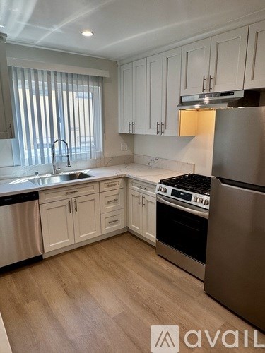 A kitchen with white cabinets and a stainless steel refrigerator.