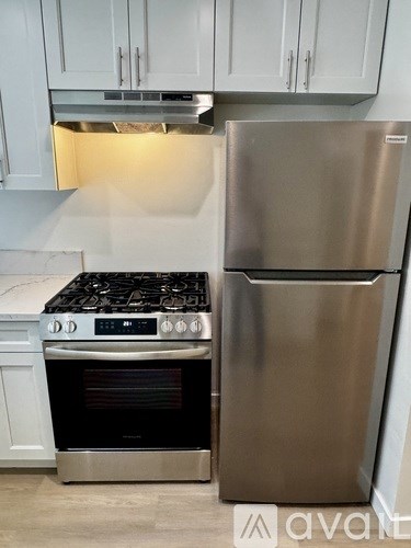 A stainless steel refrigerator stands next to a stove in a kitchen.