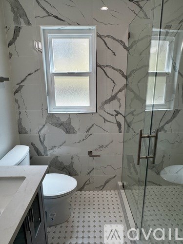 A bathroom with a marble wall and a window.