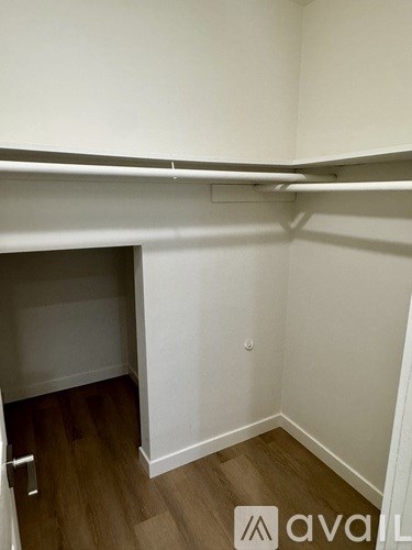 A small, empty room with wooden flooring and white walls.