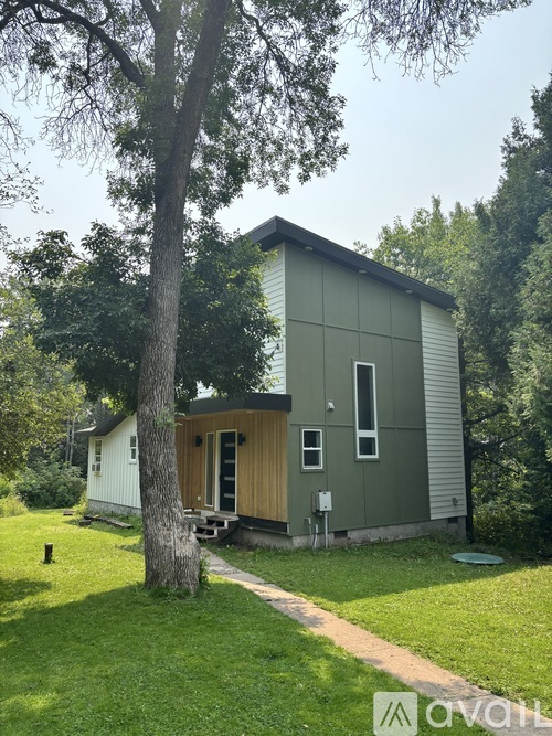 A small house with a green exterior is surrounded by trees.