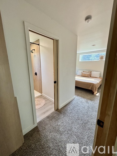 A hallway with a carpeted floor and a door leading to a bedroom.