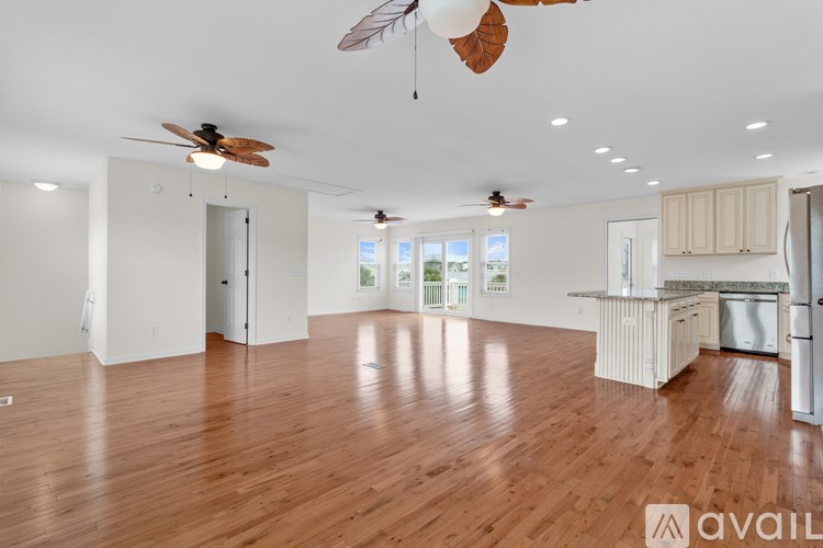 A spacious room with wooden floors and two ceiling fans.