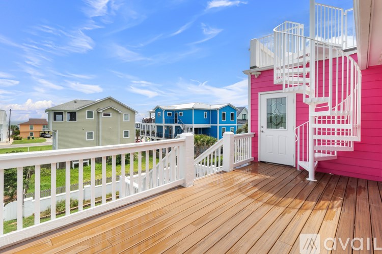 A pink house with a white fence and a balcony.