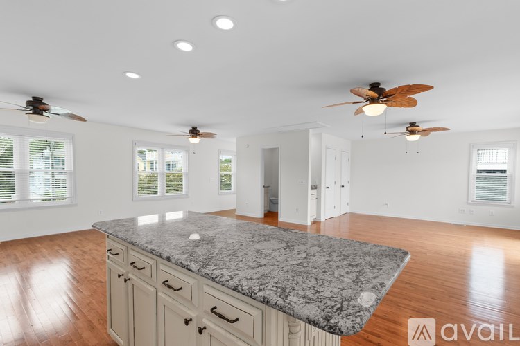 A spacious kitchen with a marble countertop and ceiling fans.
