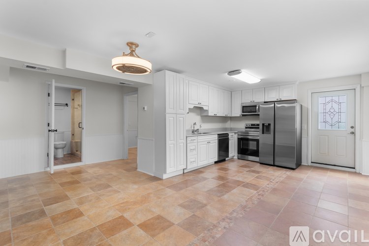 A kitchen with tile flooring and white cabinetry.