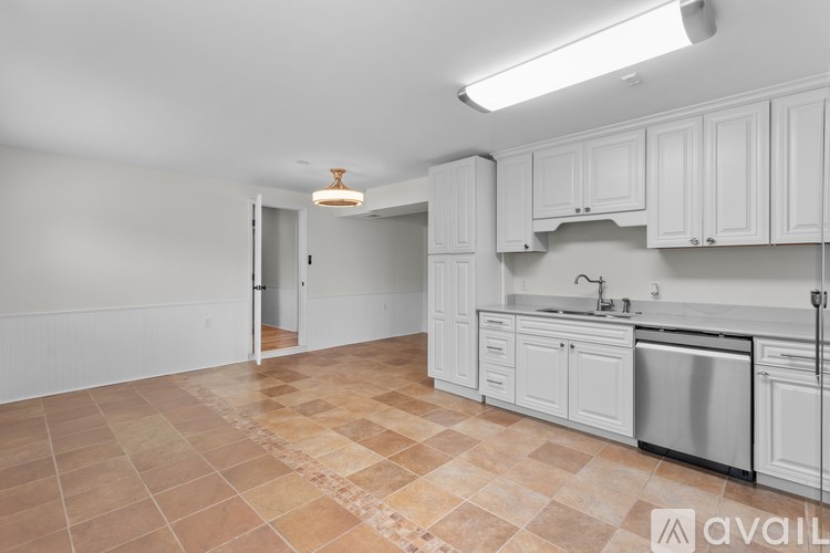 A kitchen with white cabinets and a tiled floor.