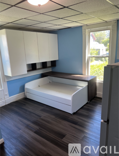A room with a white bed and wooden floors.