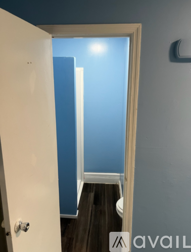 A white door is open to a room with a blue wall.
