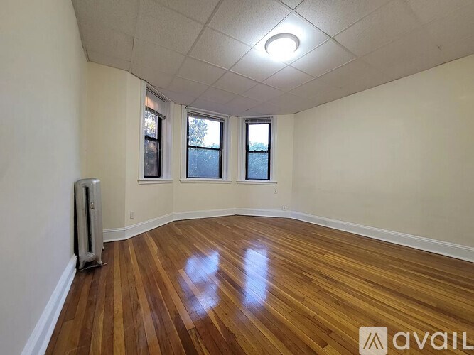 A room with wooden floors and a window with a view of a tree.