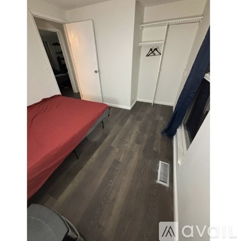A room with a red bed and a white door.