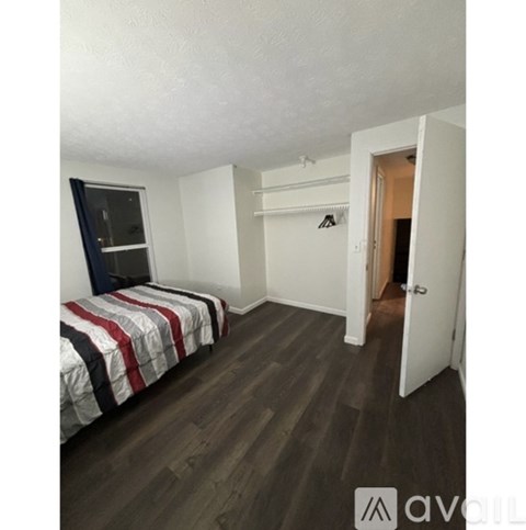 A bedroom with a bed, a window, and a door.
