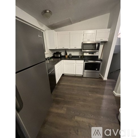 A kitchen with white cabinets and a wooden floor.