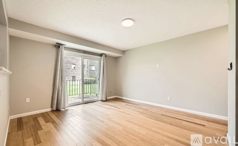 A room with wooden flooring and a sliding glass door leading outside.