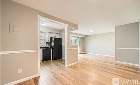 A kitchen with a black refrigerator and wooden floors.