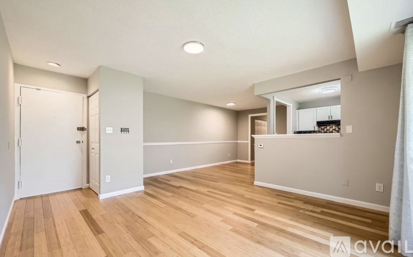 A spacious room with wooden flooring and white walls.