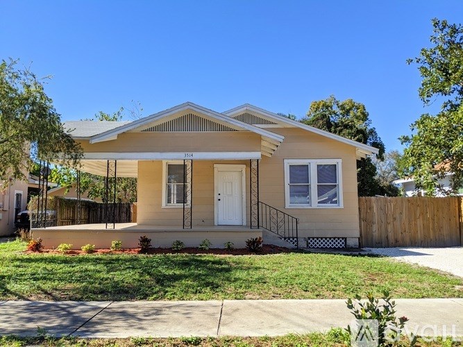 A small beige house with a white door and windows.