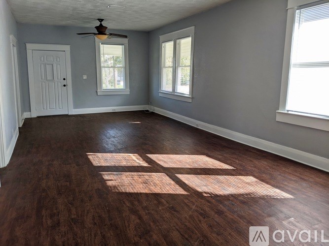A room with a ceiling fan and two windows.