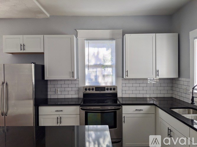 A kitchen with white cabinets and a black countertop.
