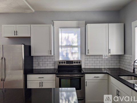 A kitchen with white cabinets and a black countertop.