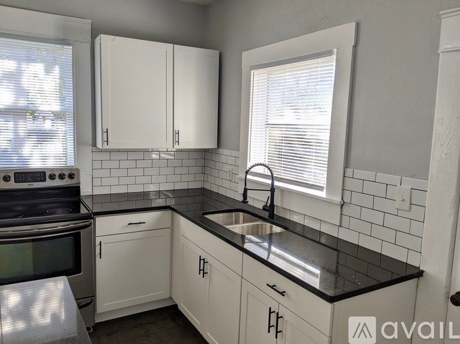 A kitchen with white cabinets and black countertops.