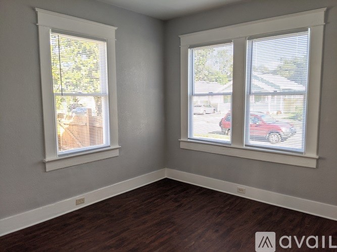 A room with two windows and wooden flooring.