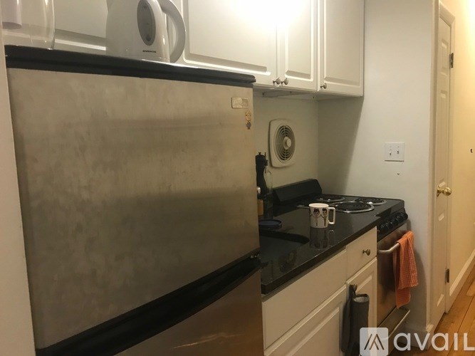 A kitchen with a stainless steel refrigerator and black countertops.